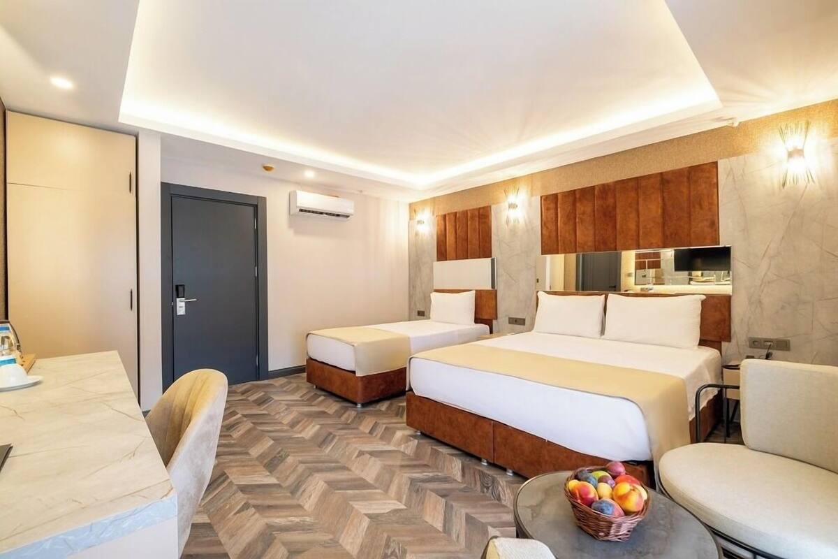 Quarto de hotel com duas camas, uma mesa de jantar e um pequeno espaço de estar.