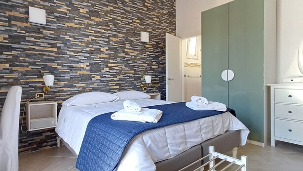 Ein modernes Hotelzimmer mit Bett, Nachttischen, Schreibtisch und Kleiderschrank.
