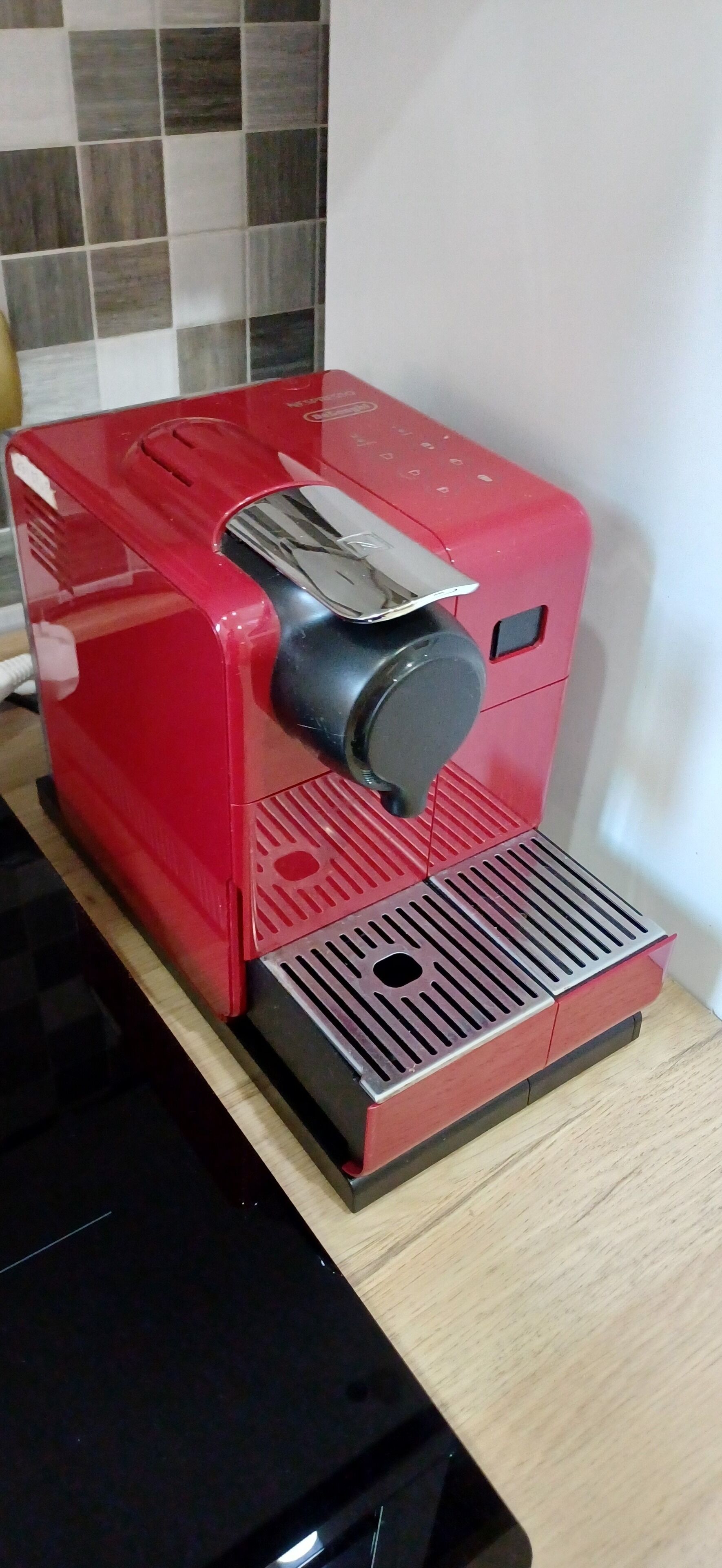 Une machine à café rouge posée sur un comptoir en bois.