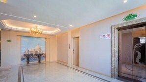 Ein Hotelgang mit einem Kronleuchter, einem Stadtbild-Wandgemälde und einem Rauchverbotsschild.