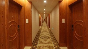 Ein Hotelgang mit Holztüren, einem gemusterten Teppich und eingelassener Beleuchtung.