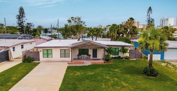 A single-story house with a front porch, a small lawn, and a palm tree. - Daytona Beach Shores House - walk to beach & restaurants (Daytona Beach)