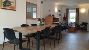 A dining area with a wooden table and black chairs, a vase with flowers, and a guitar on the wall.