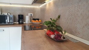 A kitchen with a microwave, coffee maker, and a bowl of oranges.