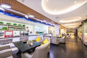 Un moderno vestíbulo de hotel con una recepción, zona de estar y un bar.