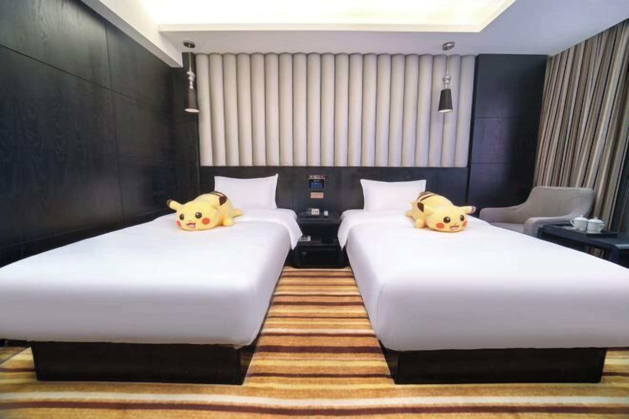 A hotel room with two beds, a large window, a flat-screen TV, and a minibar.