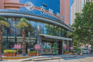 A modern hotel with a curved facade, large windows, and a prominent entrance with a covered walkway. - Gulong Hotel (Hanzhong High-speed Railway Station Wanbang) (Hanzhong)