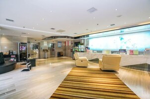 A modern lobby with a reception desk, seating area, and a large digital display.
