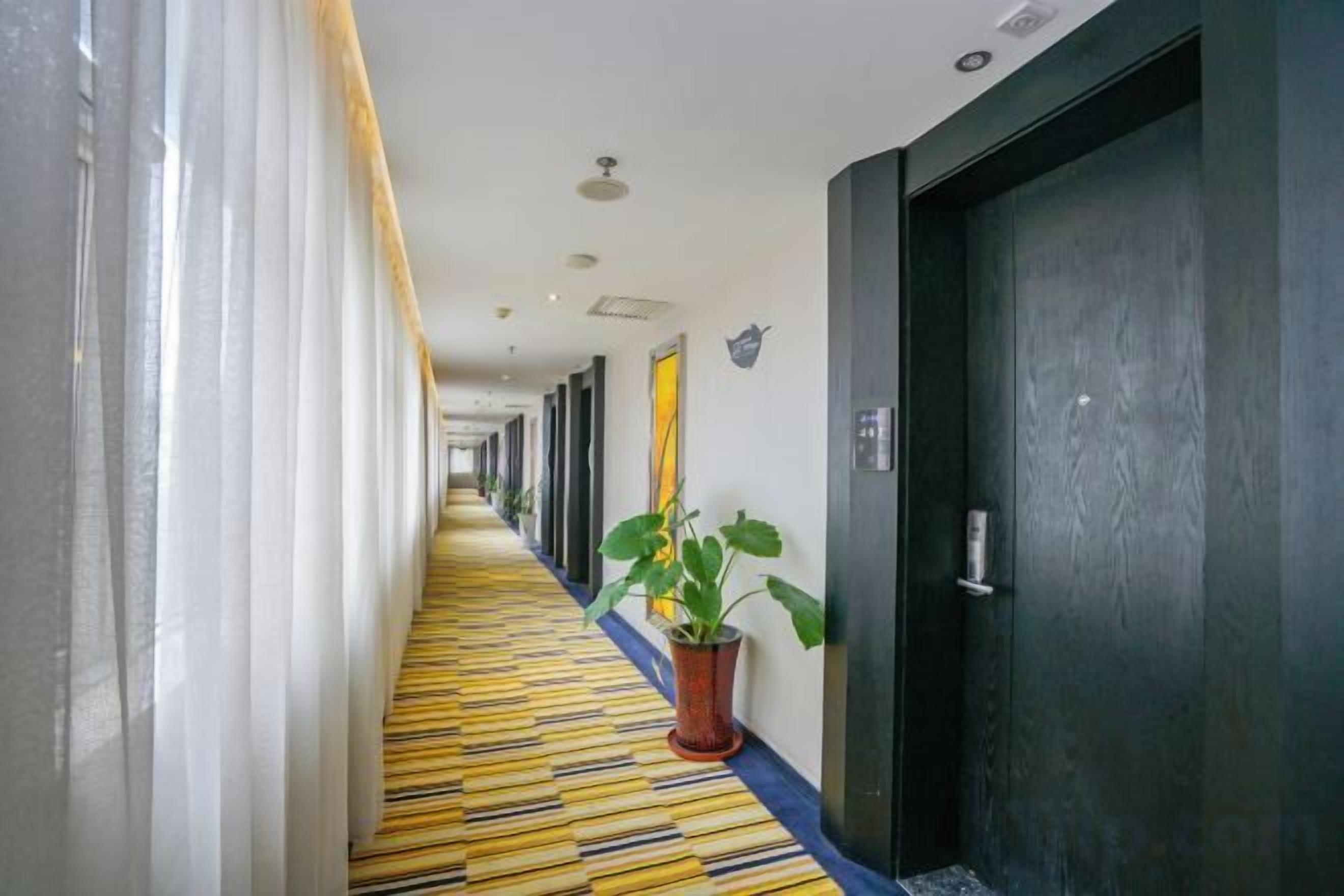 A hotel hallway with doors on one side and a patterned carpet.