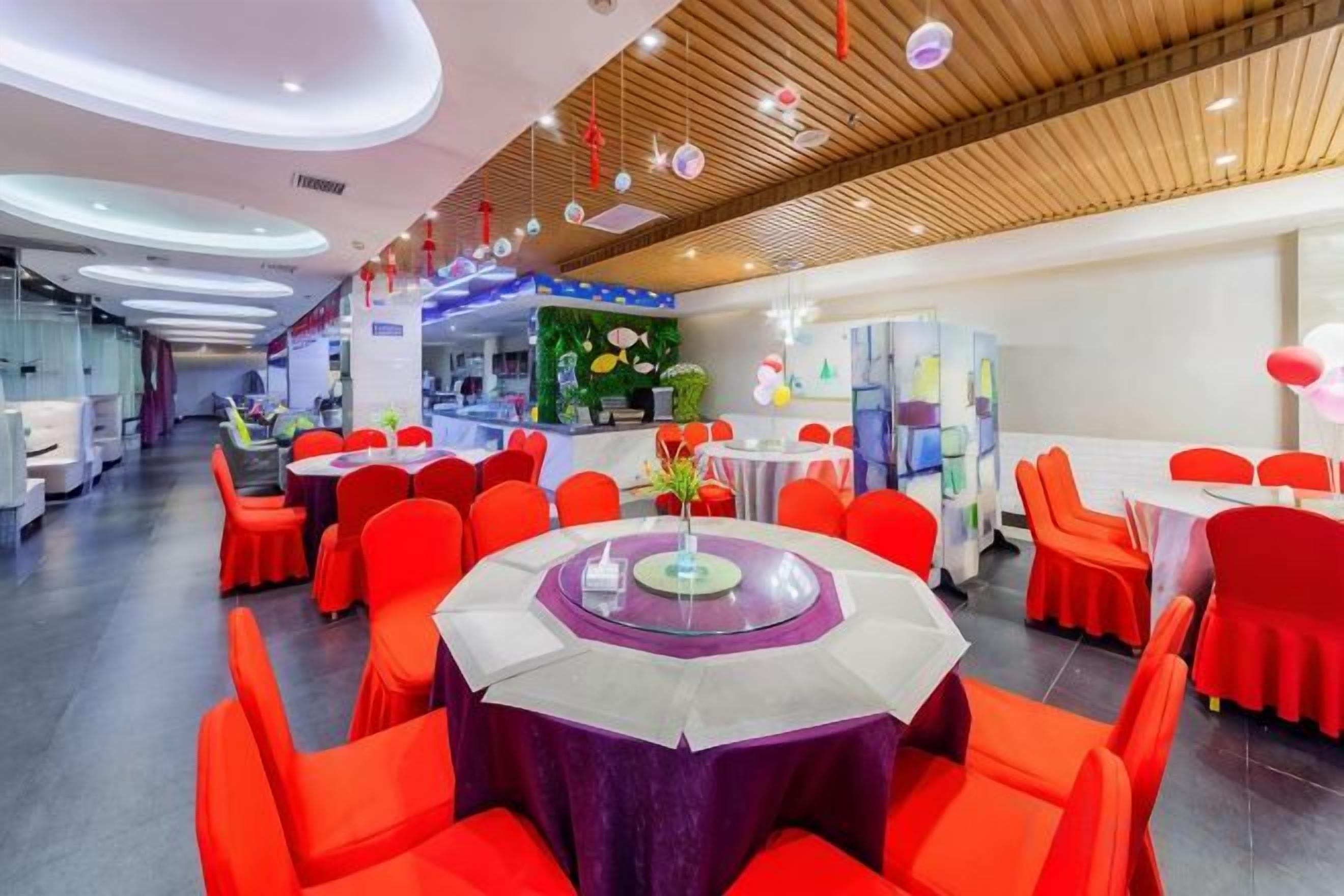 Un comedor moderno con mesas redondas y sillas naranjas, que destaca un elemento decorativo central.
