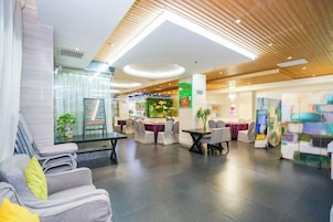 Un moderno vestíbulo de hotel con áreas de estar, un comedor y una recepción.