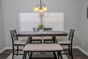 A dining area with a dark wooden table, four chairs, a bench, and a potted plant. - Modern 4BR Home - Very Spacious - Minutes from Georgia International Horse Park (Conyers)