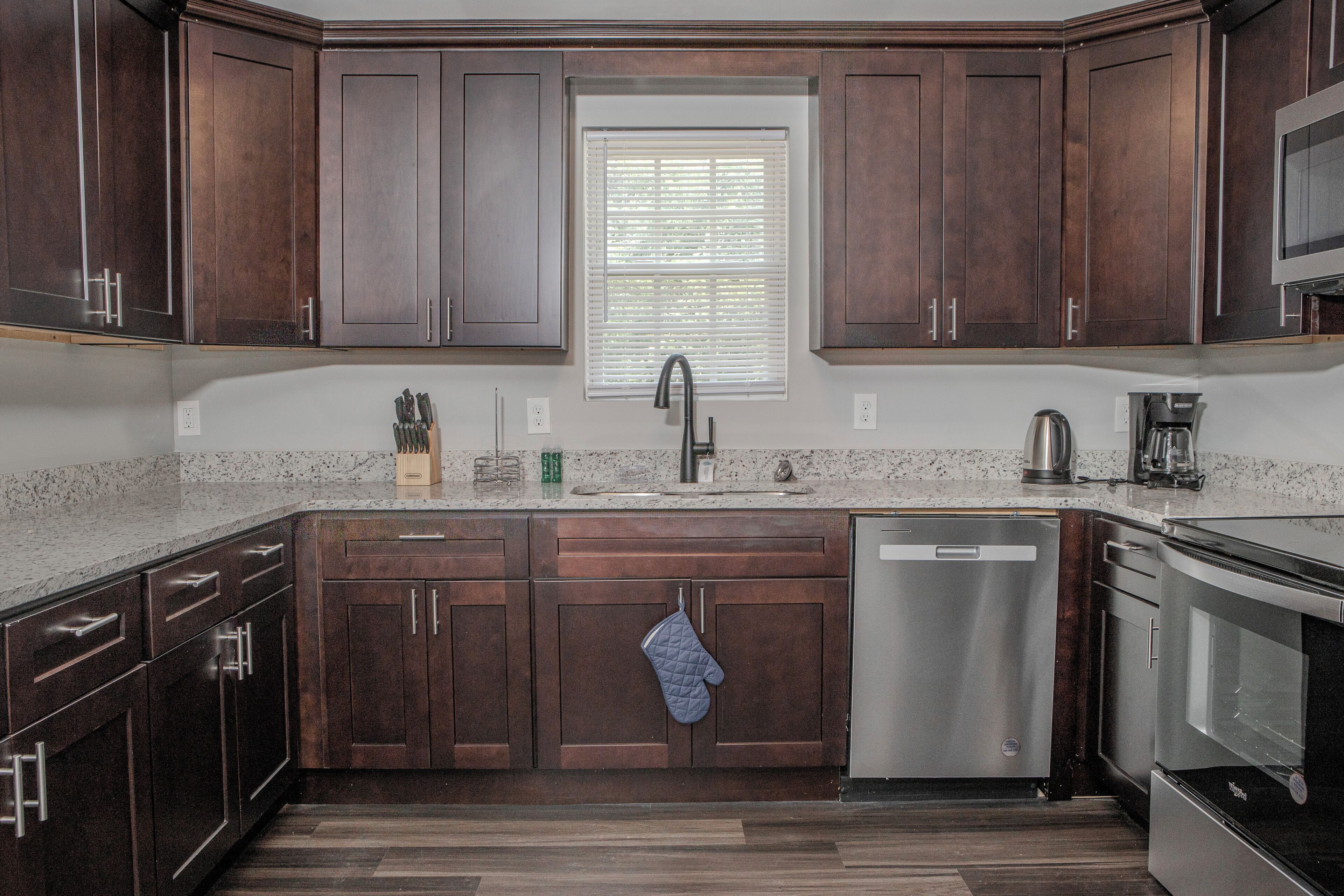 A kitchen with dark wood cabinets, a stainless steel dishwasher, and a built-in oven.