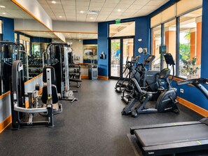 A gym with cardio machines, weightlifting equipment, and mirrors.