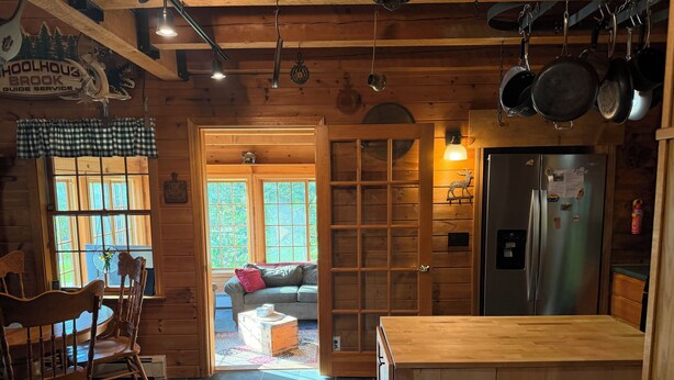 L’intérieur d’un chalet en bois comprend un coin repas, un canapé, une cuisine équipée d’un réfrigérateur et une grande fenêtre.