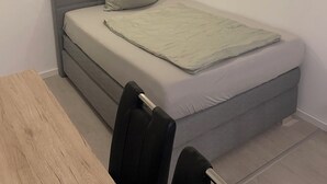 A small, modern room with a single bed, a wooden table, and a chair. - Apartmenats Mitte Messe und Zentrum (Nuremberg)