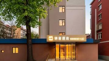 A hotel entrance with a modern facade, a tree in front, and a signboard above the entrance.