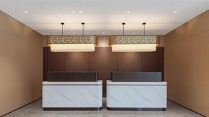 A reception area with two marble reception desks, pendant lighting, and a wooden panel wall. - Homeinn Ease Hotel (Beijing Capital Gymnasium Baishiqiao South Subway Station) (Beijing)
