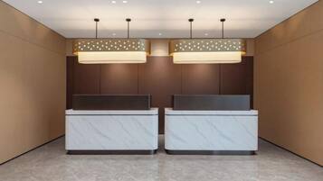 A reception area with two marble reception desks, pendant lighting, and a wooden panel wall.