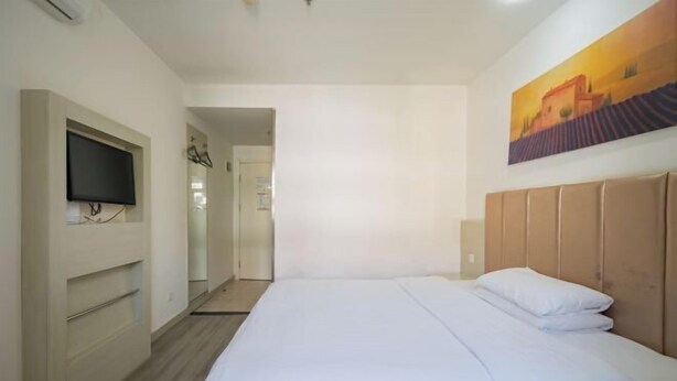 A hotel room with a bed, a TV mounted on the wall, and a painting above the bed. - Homeinn Ease Hotel (Beijing Capital Gymnasium Baishiqiao South Subway Station) (Beijing)