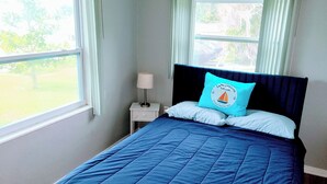 A bedroom with a bed, a nightstand, a lamp, and a window with curtains. - Cozy 1 Bedroom home on Beautiful Lake Alfred (Lake Alfred)
