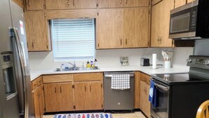 A kitchen with wooden cabinets, a stainless steel refrigerator, a microwave, a dishwasher, and a stove. - Cozy 1 Bedroom home on Beautiful Lake Alfred (Lake Alfred)