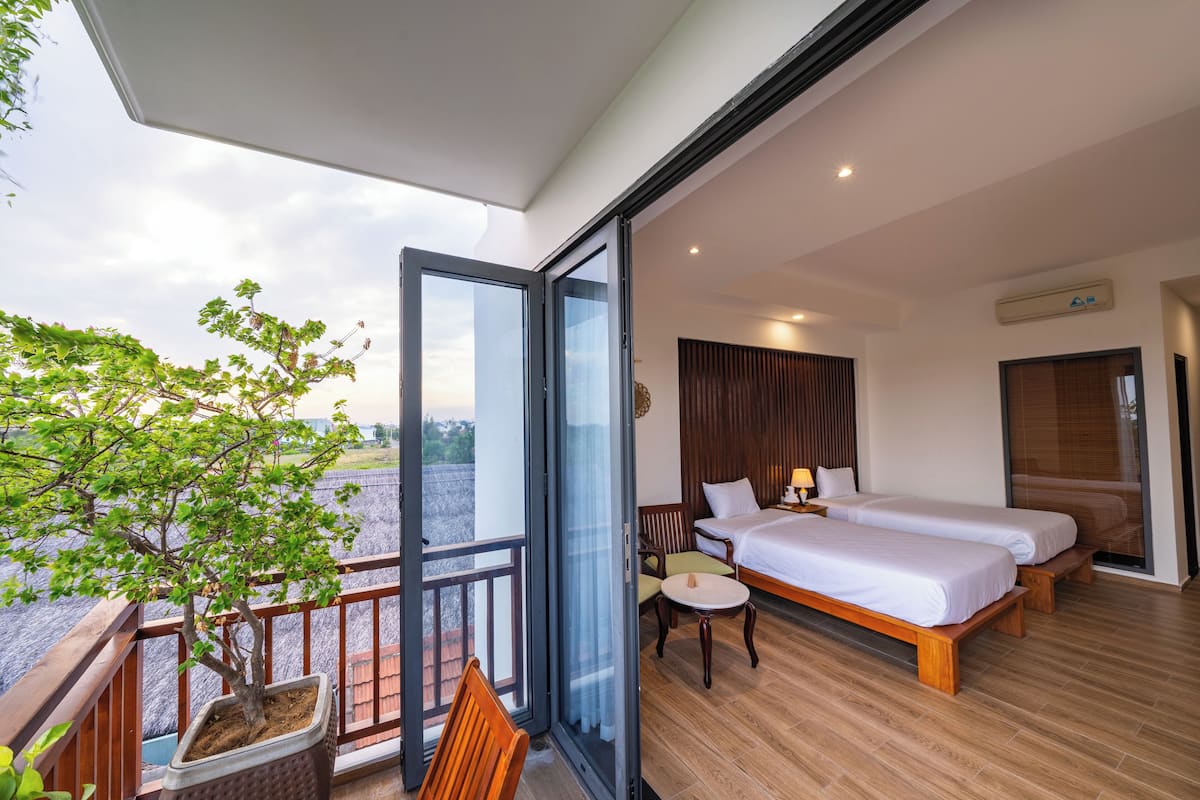 Ein Balkon mit einem Blumentopf, einem Bett mit zwei Kissen, einem kleinen Tisch und einem Stuhl.