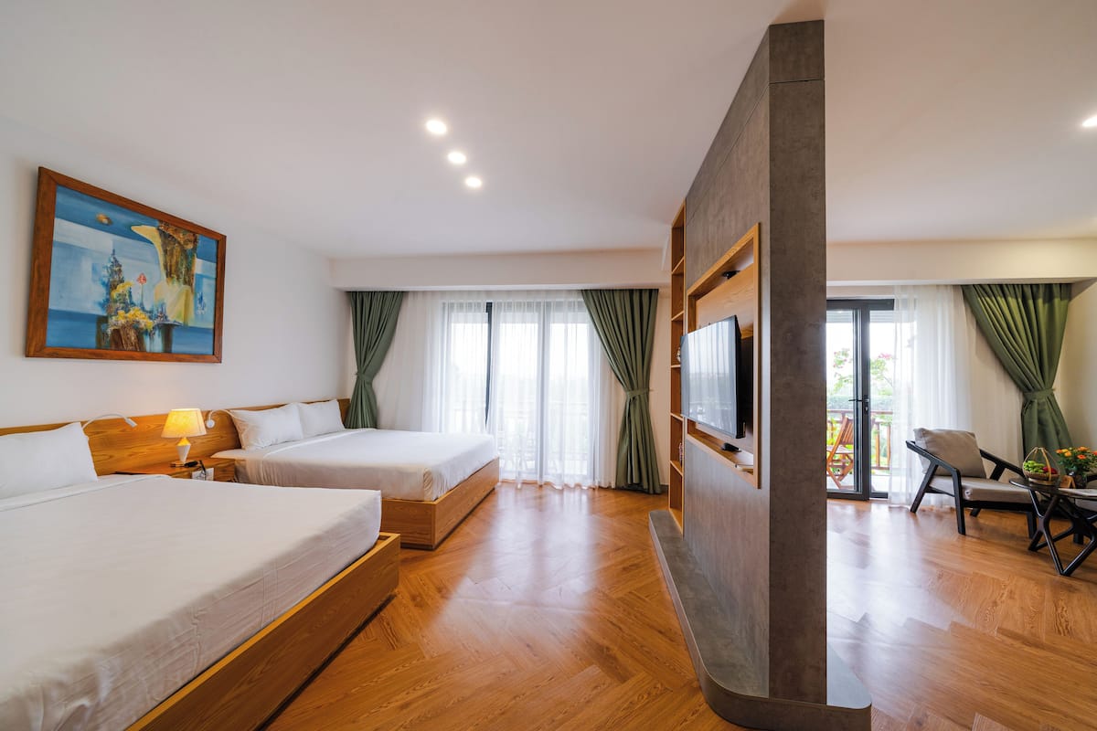 Ein Hotelzimmer mit zwei Betten, einem Fernseher, Holzboden und einem Bild an der Wand.