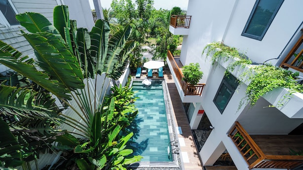 Un edificio moderno con piscina rodeada de exuberante vegetación.