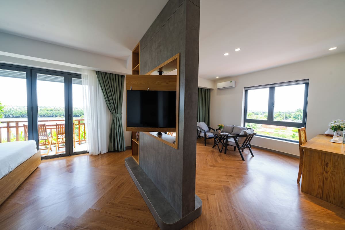 Ein modernes Hotelzimmer mit einem großen Bett, einem an der Wand montierten Fernseher, einem Balkon mit Aussicht und einer Essecke mit Tisch und Stühlen.