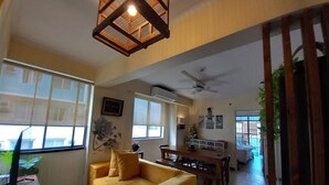 Uma sala de estar ampla com um sofá amarelo, uma mesa de jantar e um ventilador de teto.