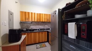 Uma cozinha compacta com armários de madeira, geladeira de aço inoxidável e micro-ondas.