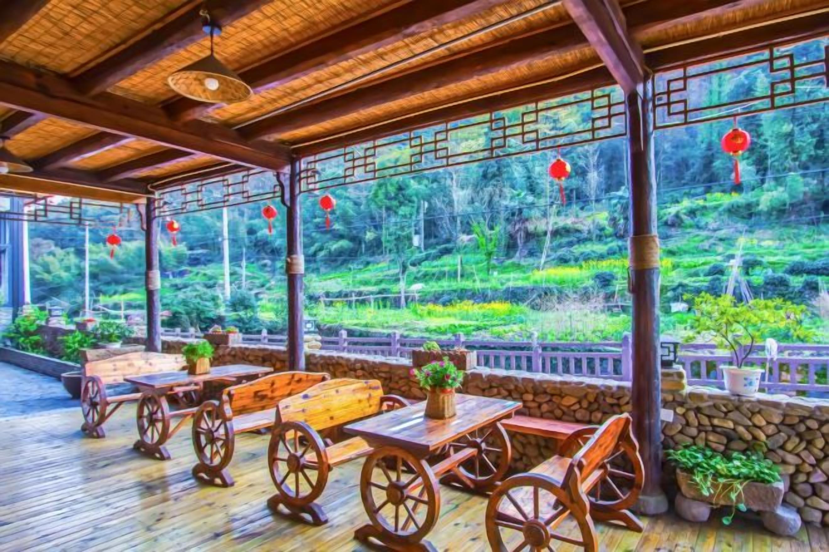 A covered outdoor seating area with wooden furniture and a view of a lush garden.