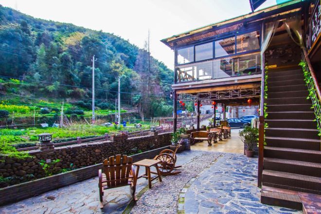A restaurant with outdoor seating, a staircase, and a view of a green hillside.