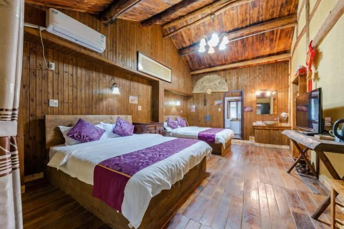 A wooden room with two beds, a sink, and a television.