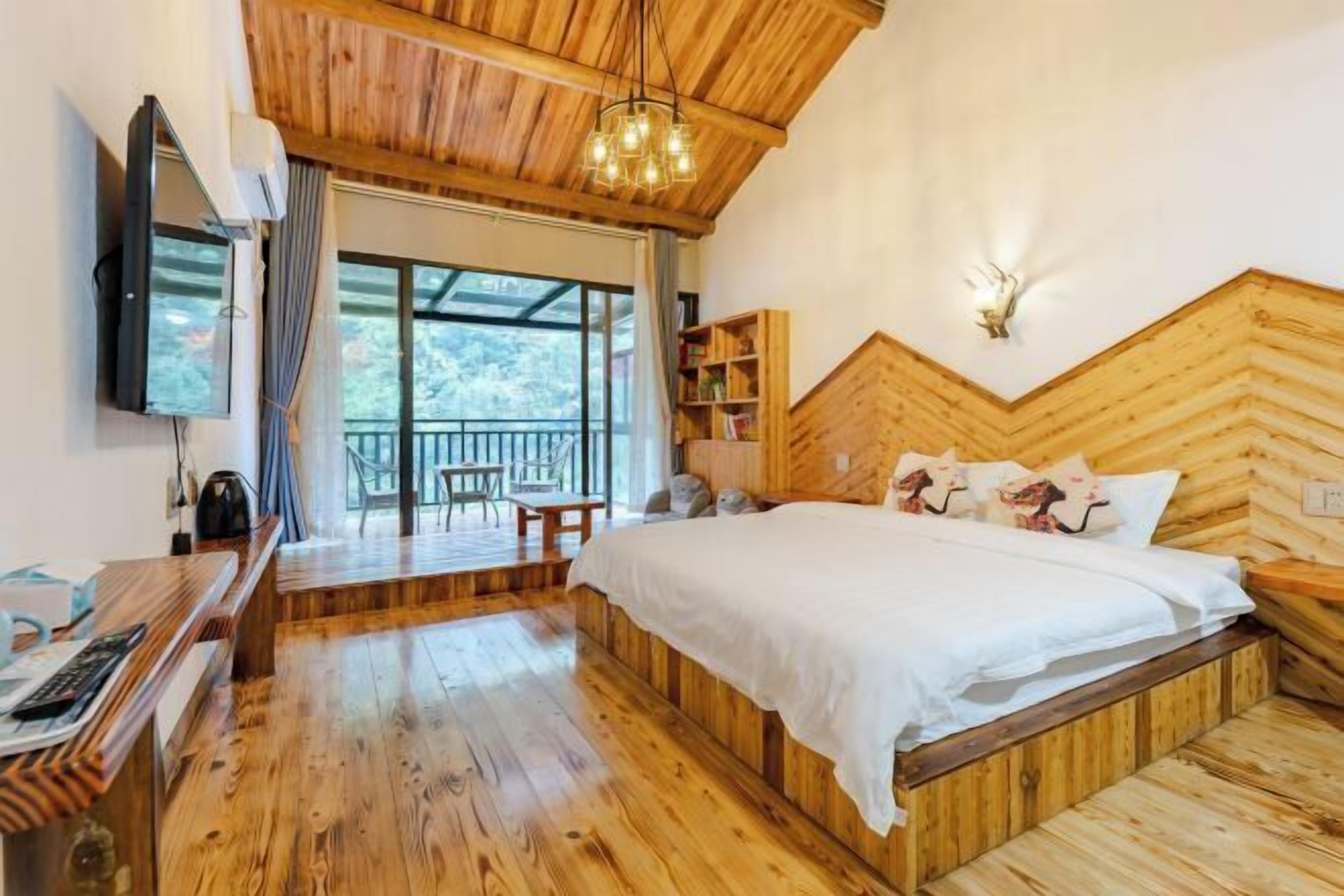 A wooden room with a bed, a desk, and a TV.