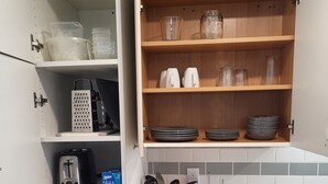 A kitchen with white cabinets, a marble countertop, and a wooden shelf with glassware and plates. - Practical-ly home
2 bedroom  quiet and peaceful suite.
tons of natural light
 (Edmonton)