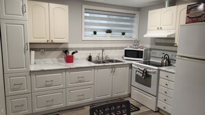 A modern kitchen with white cabinets, a microwave, stove, and a sink. - Practical-ly home
2 bedroom  quiet and peaceful suite.
tons of natural light
 (Edmonton)