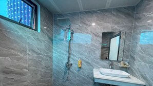 Ein modernes Badezimmer mit einer gläsernen Duschkabine, einem weißen Waschbecken und einem Spiegel.