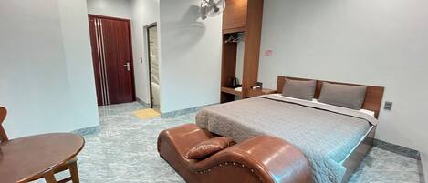 Una habitación de hotel con cama, escritorio, silla y una pequeña mesa.