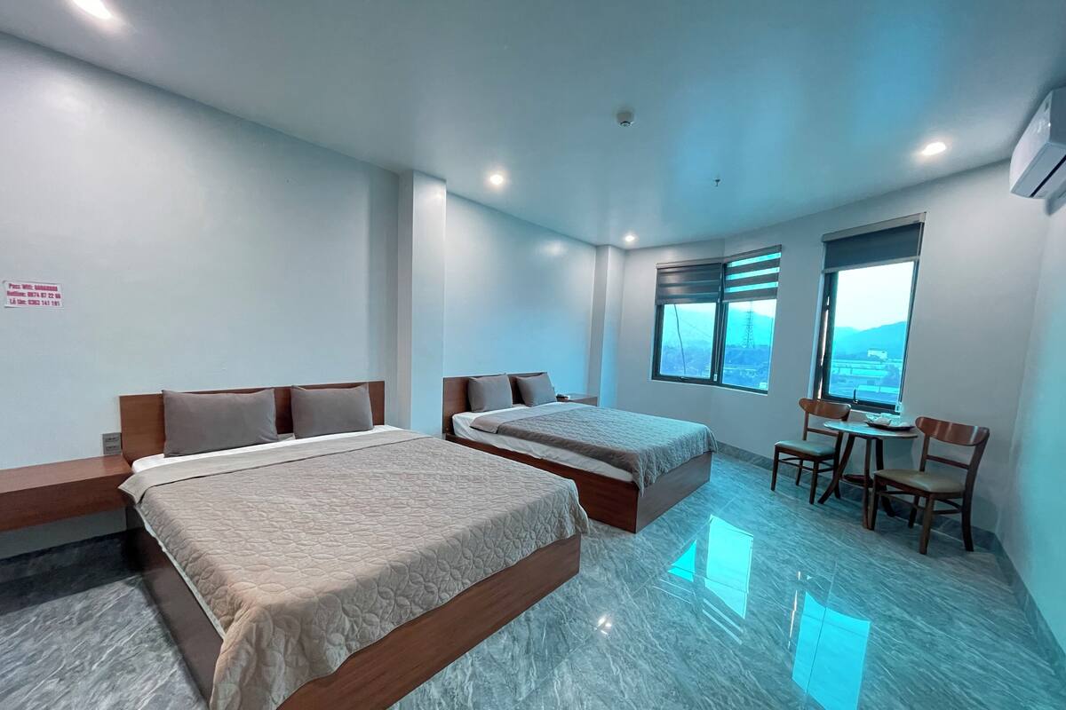 A hotel room with two beds, a desk, and a chair.