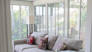 A living room with a beige sofa, patterned cushions, and a red side table.