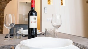 A table set with white plates, a wine bottle, and glasses in a stone-walled room with an arched doorway.