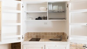 A kitchen with white cabinets, a black countertop, a sink, and a backsplash.