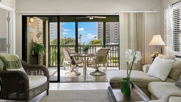 Un salon moderne avec un canapé, une table à manger et des chaises, un balcon offrant une vue sur la ville et une plante en pot.