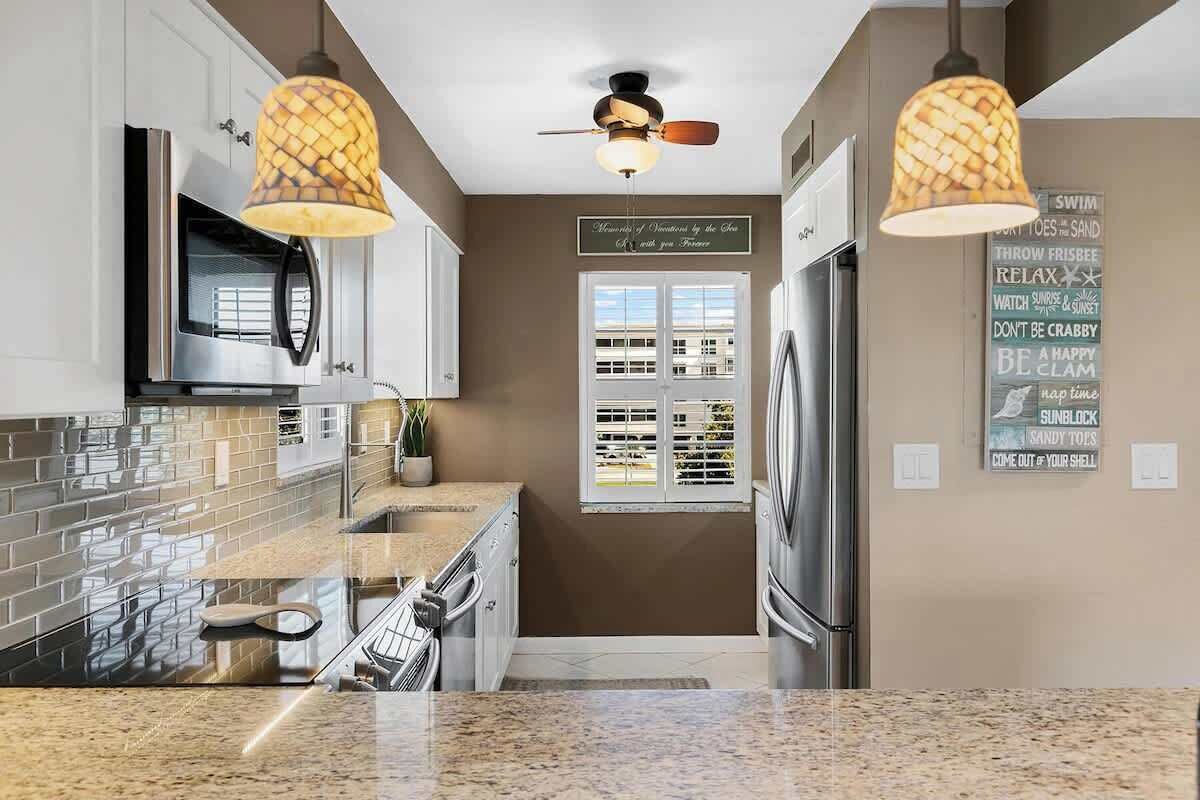 A modern kitchen with granite countertops, stainless steel appliances, and pendant lighting.