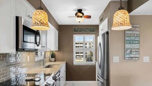 Une cuisine moderne dotée de plans de travail en granit, d’appareils électroménagers en acier inoxydable et de luminaires suspendus.