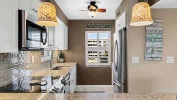 A modern kitchen with granite countertops, stainless steel appliances, and pendant lighting.