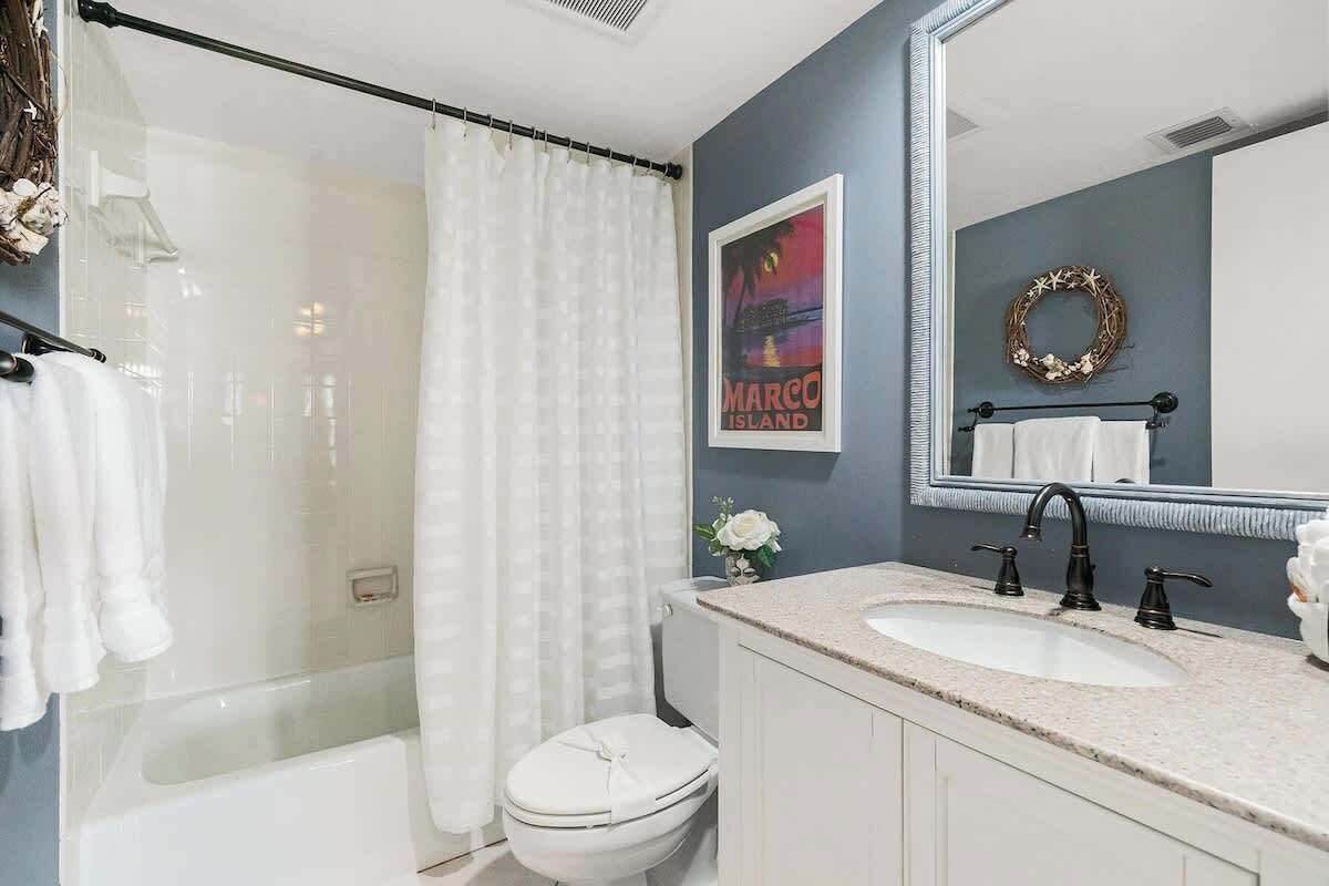 A modern bathroom with a glass shower, white toilet, and a vanity with a sink and mirror.