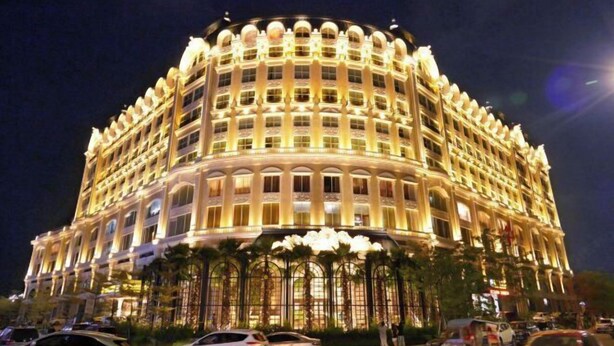 A large, illuminated hotel with a circular facade, multiple balconies, and a central entrance with a canopy. - Noble Hotel (Shanwei)